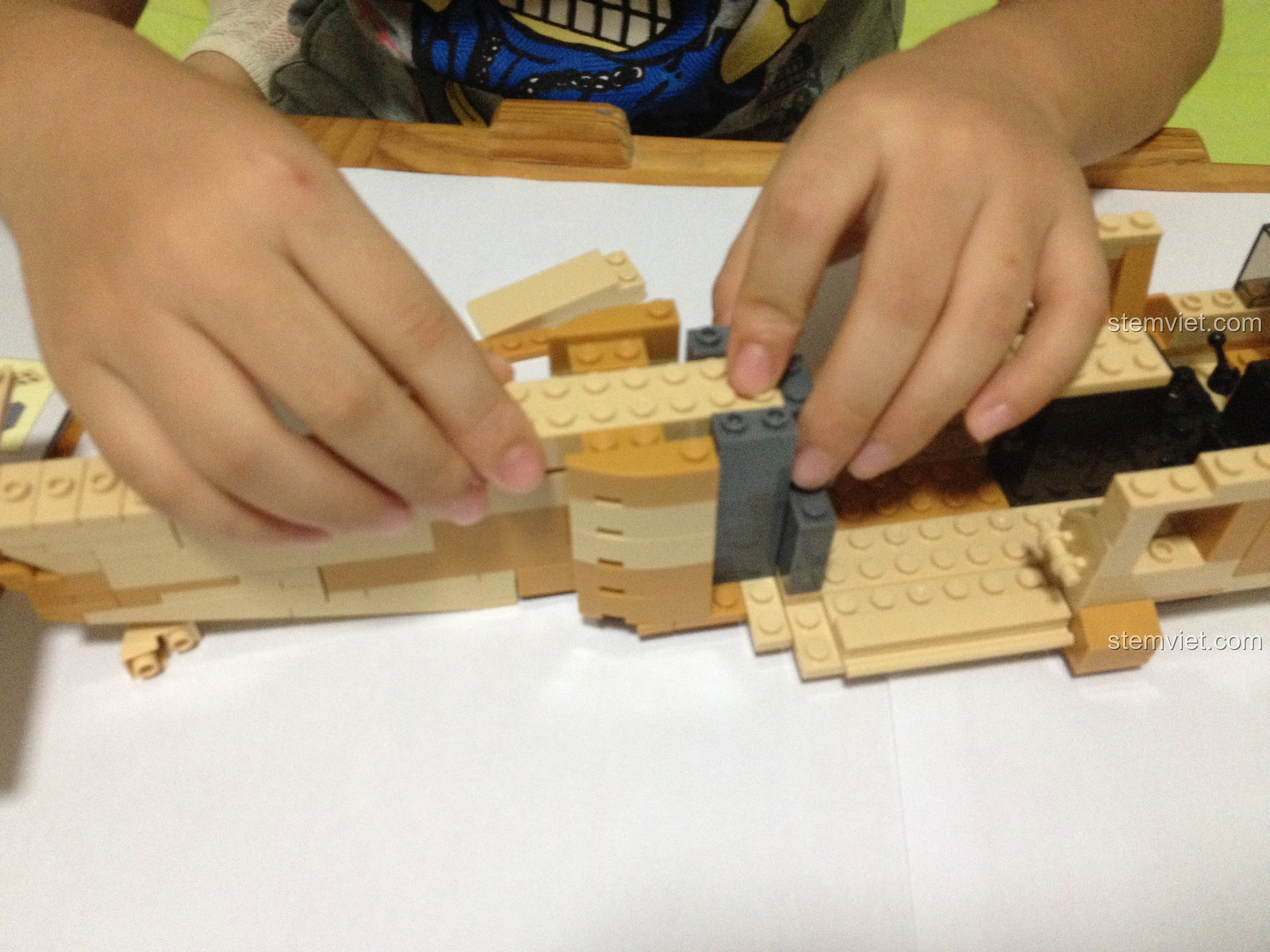 Bé trai tiếp tục lắp ráp phần cánh của Sluban M38-B0509 Trực thăng Black Hawk UH-60L, hoàn thiện cấu trúc.