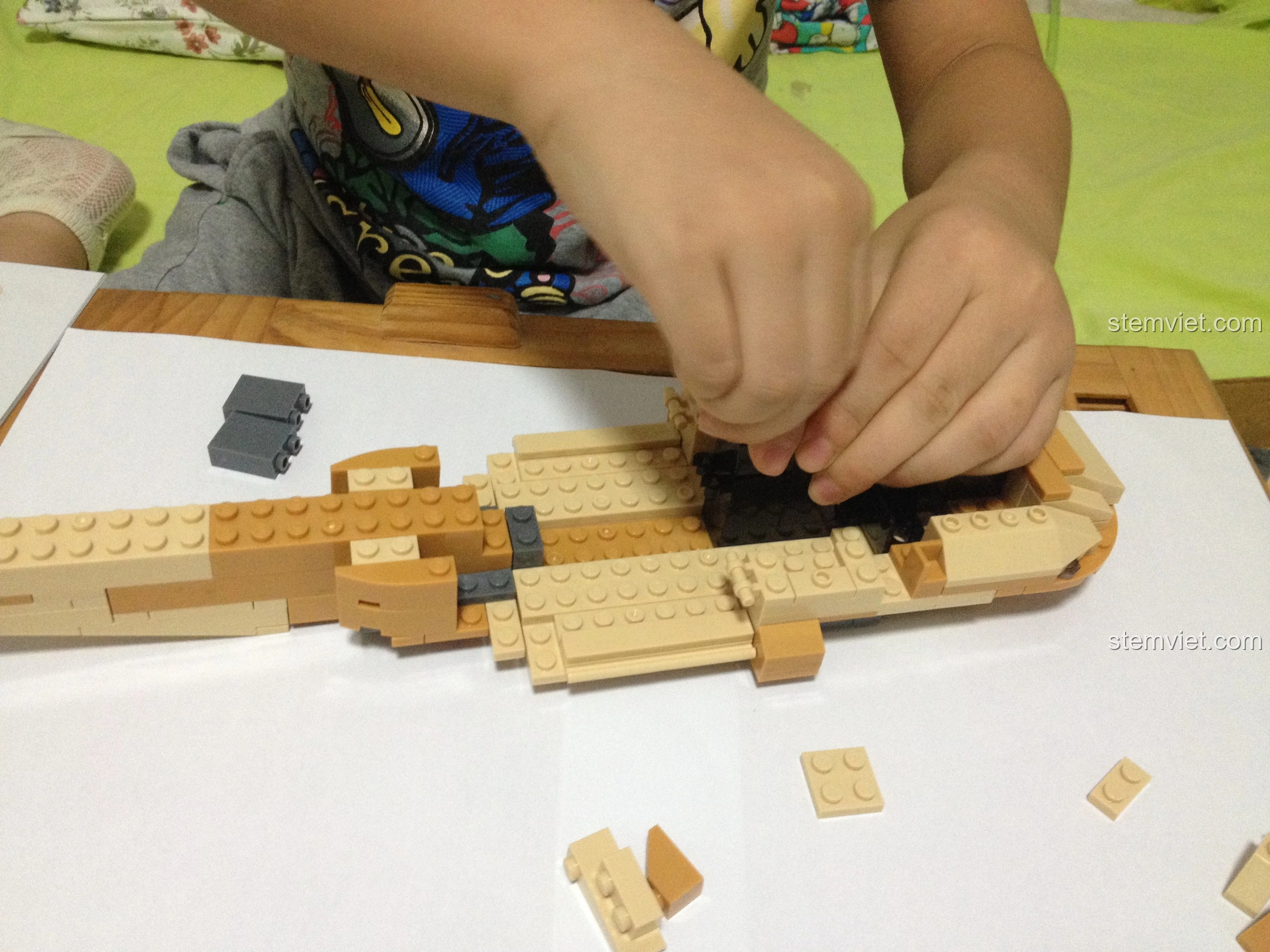 Bé trai đang lắp các chi tiết nhỏ vào phần thân của Sluban M38-B0509 Trực thăng Black Hawk UH-60L.