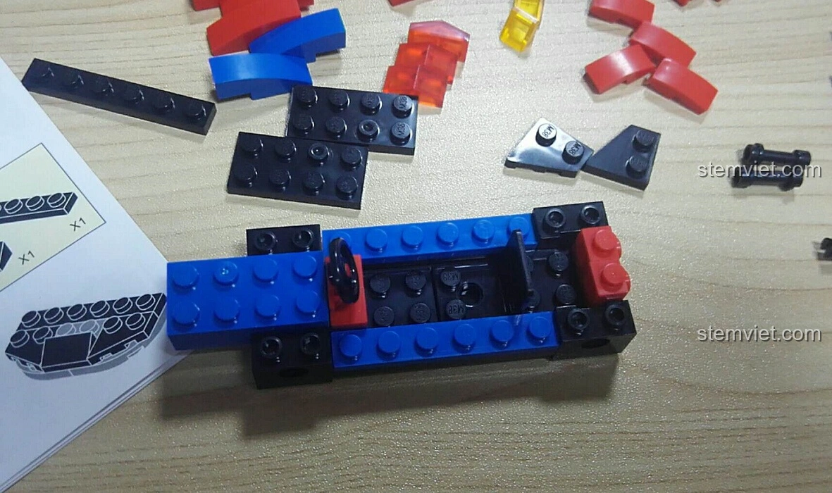 Bắt đầu quá trình lắp ráp bộ Sluban M38-B0633E Xe Đua Tốc Độ Cánh Bướm, với phần khung xe cơ bản đang được hình thành.