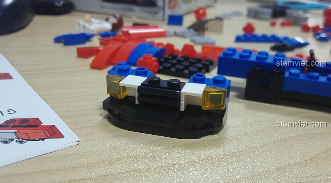 Chi tiết phần đầu xe của mô hình Sluban M38-B0633E Xe Đua Tốc Độ Cánh Bướm đang được lắp ráp, với đèn pha và lưới tản nhiệt.