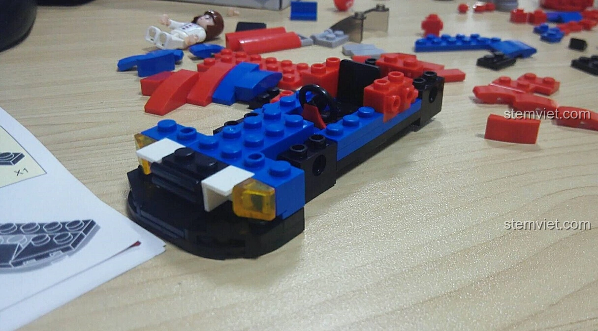 Quá trình lắp ráp phần thân xe của bộ Sluban M38-B0633E Xe Đua Tốc Độ Cánh Bướm, với các chi tiết màu xanh và đỏ.