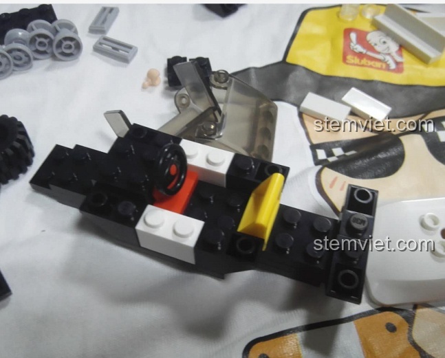 Bắt đầu quá trình lắp ráp khung xe của bộ Sluban M38-B0639 Ô tô Cảnh Sát Tuần Tra, các chi tiết được sắp xếp gọn gàng.