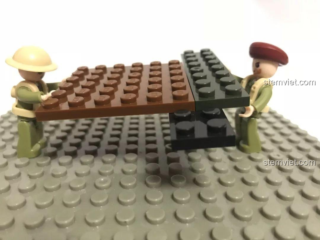 Đồ chơi xây dựng M38B0713, hai minifigure đang giữ một đế lắp ráp, thể hiện khả năng tương thích LEGO®.