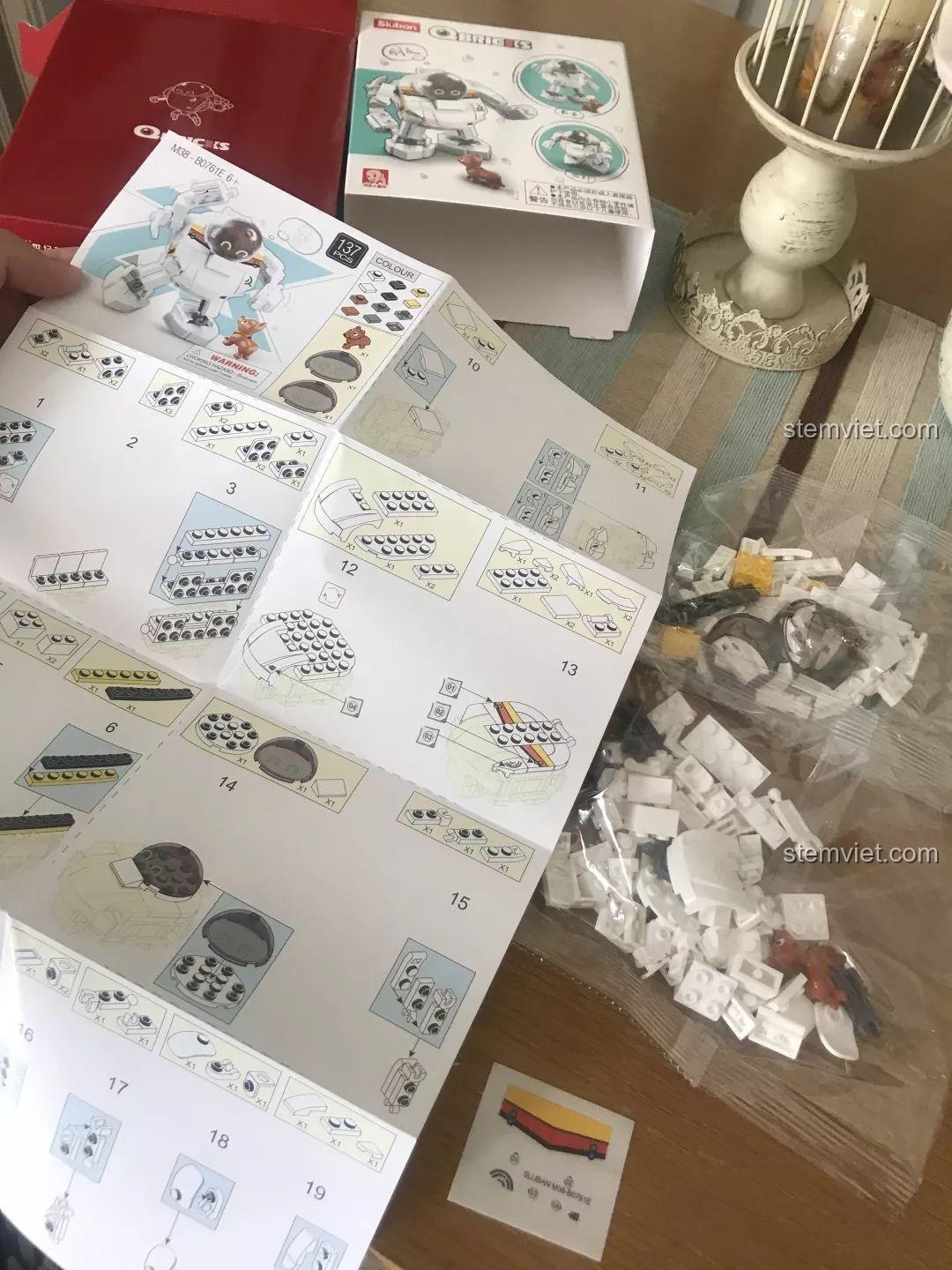 Các túi linh kiện và sách hướng dẫn lắp ráp của bộ Sluban M38-B0761E Robot Q-Bricks được đặt cạnh hộp. Đánh giá Sluban M38-B0761E Robot Q-dễ thương.