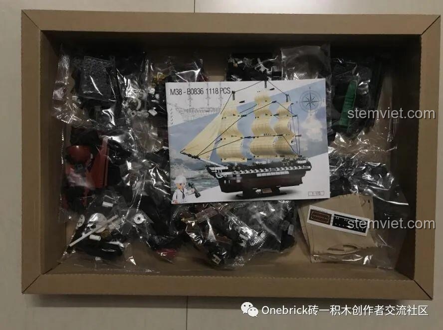 Bên trong hộp đồ chơi mô hình Tàu chiến USS Constitution Sluban, cho thấy các túi chi tiết và sách hướng dẫn.