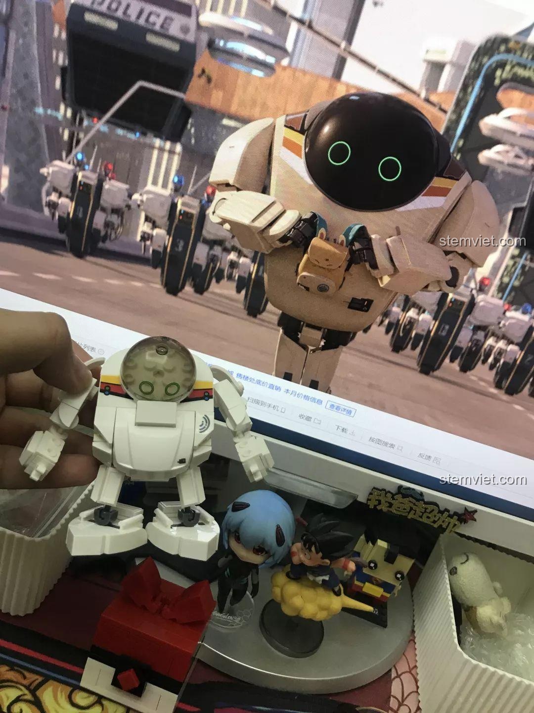 Robot Q-Bricks Sluban M38-B0761E được đặt cạnh màn hình chiếu cảnh phim Future Robot City, thể hiện sự giống nhau với nhân vật 7723. Nhận xét Sluban M38B0761E Robot Q-thông minh.