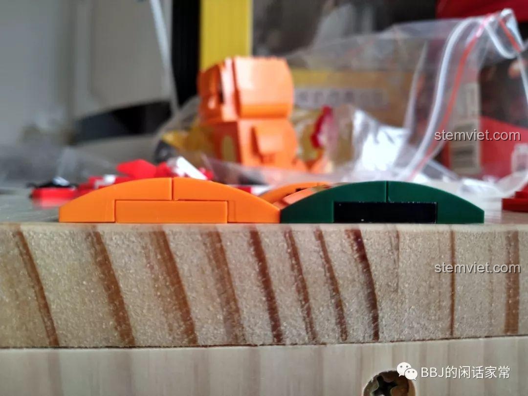 So sánh trực tiếp giữa mảnh ghép cong của Keeppley (cam) và LEGO (xanh), làm nổi bật sự khác biệt về độ phẳng.