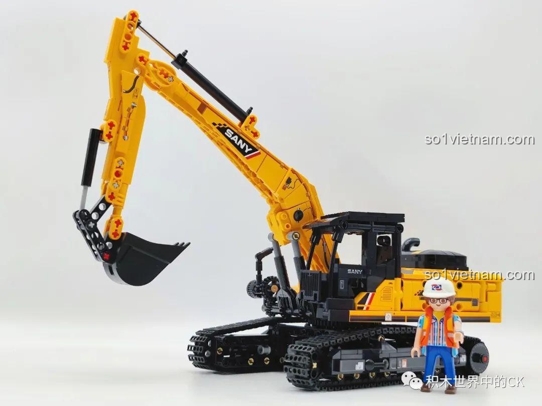 So sánh kích thước của mô hình xe xúc Sembo 712017 với một nhân vật minifigure, cho thấy tỷ lệ hoành tráng của sản phẩm.
