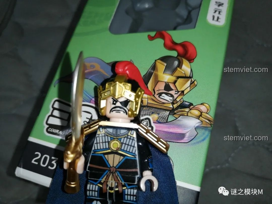 Cận cảnh minifigure Hạ Hầu Đôn đứng trước hộp của mình, thể hiện sự tương đồng giữa sản phẩm và hình ảnh quảng cáo.