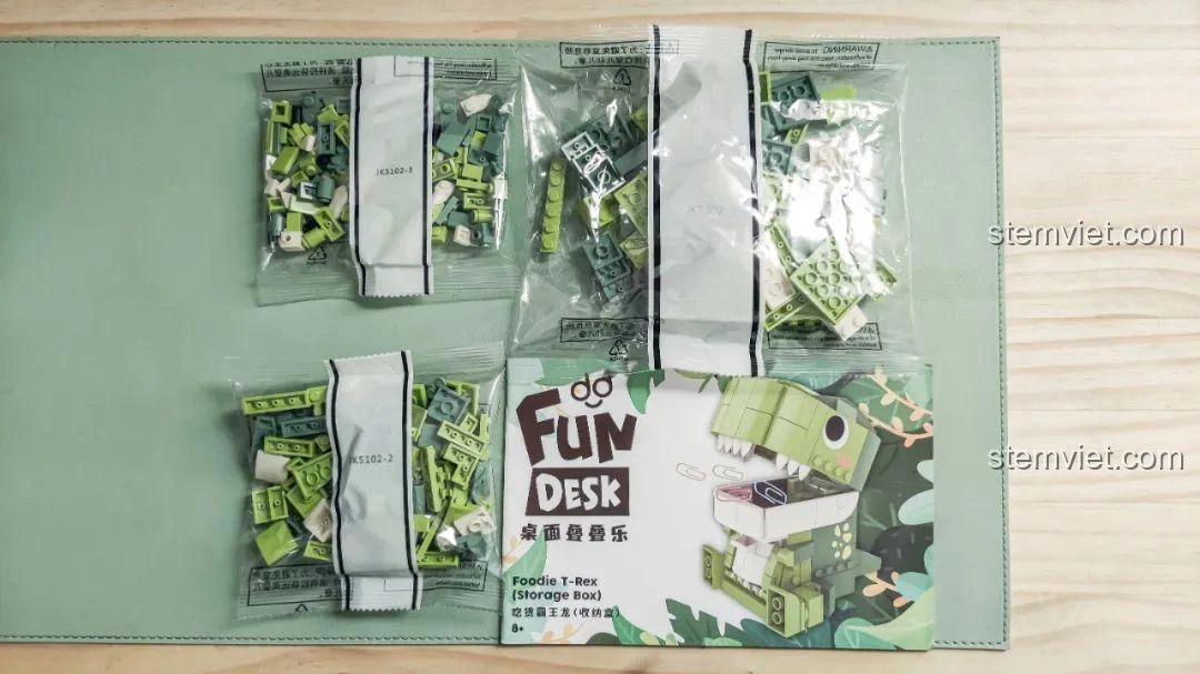 Tất cả các túi mảnh ghép và sách hướng dẫn của bộ lắp ghép Khủng long Bạo Chúa Ăn Vặt JAKI JK5102 được bày ra.