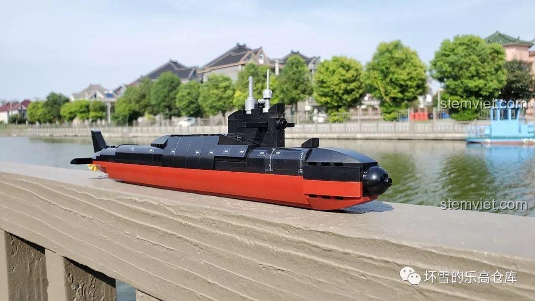 Mô hình tàu ngầm hạt nhân Type 094 Sluban M38-B0703 đã hoàn thành, đặt trên lan can gỗ cạnh hồ nước, thể hiện vẻ đẹp chân thực và chi tiết.