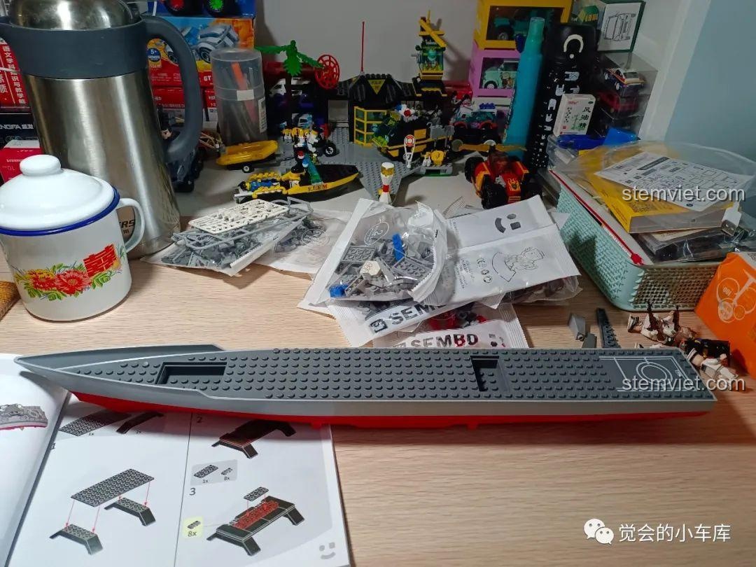 Thân tàu đúc liền khối của bộ SEMBO 202029 đặt trên sách hướng dẫn, bên cạnh là các túi chi tiết và minifigures đã lắp ráp.