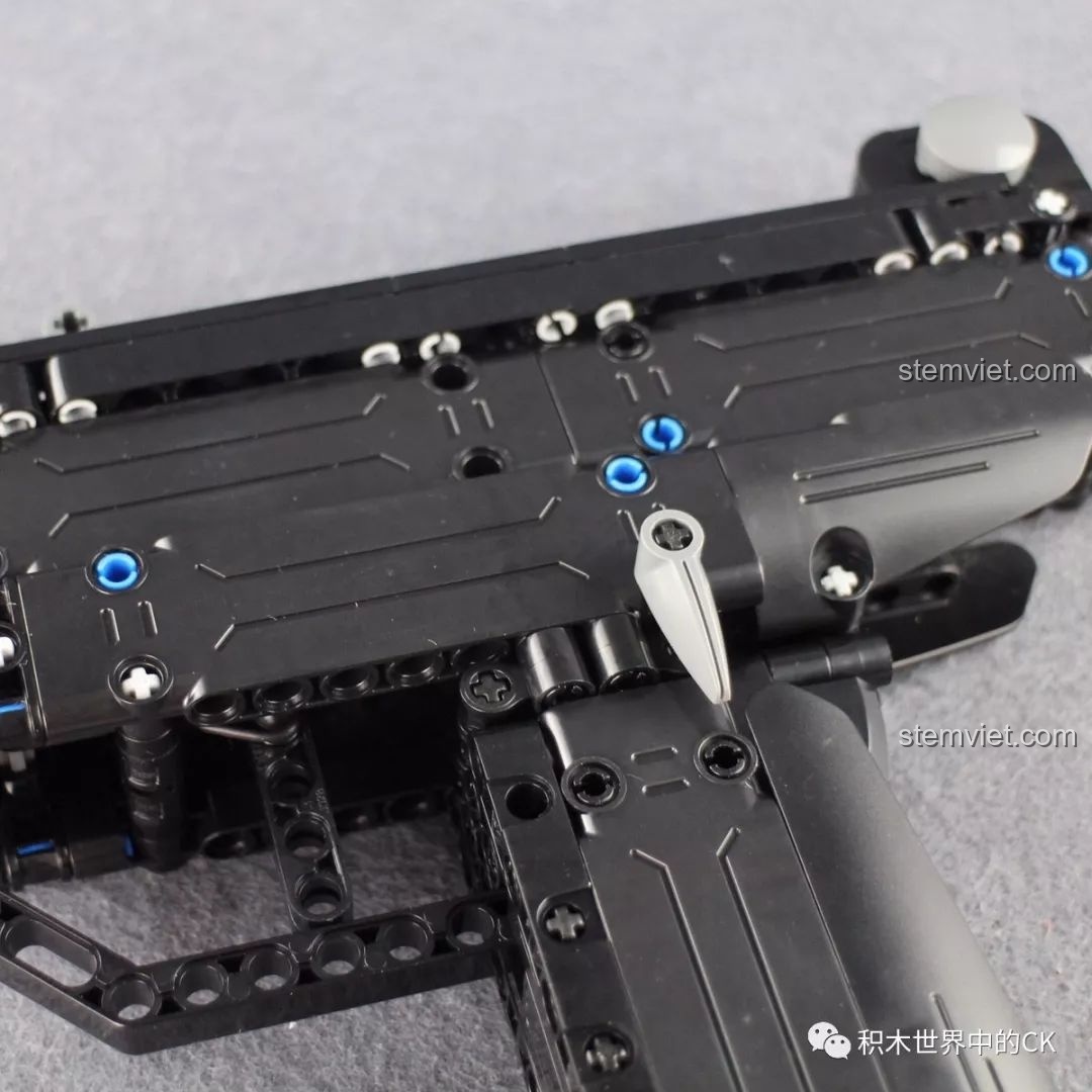 Thao tác gạt chốt khóa an toàn trên bộ đồ chơi Súng UZI CaDA, đảm bảo an toàn khi không sử dụng.