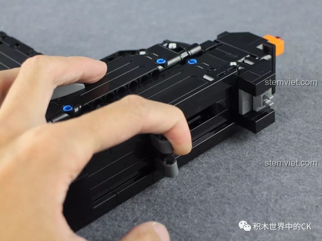 Một người đang thao tác với cần gạt lên đạn của mô hình súng UZI CaDA, thể hiện tính năng tương tác.