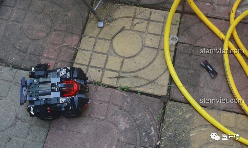 Xe Batmobile Mould King 13020 đang được chạy thử nghiệm trên sàn gạch, một mảnh cản trước bị rơi ra.