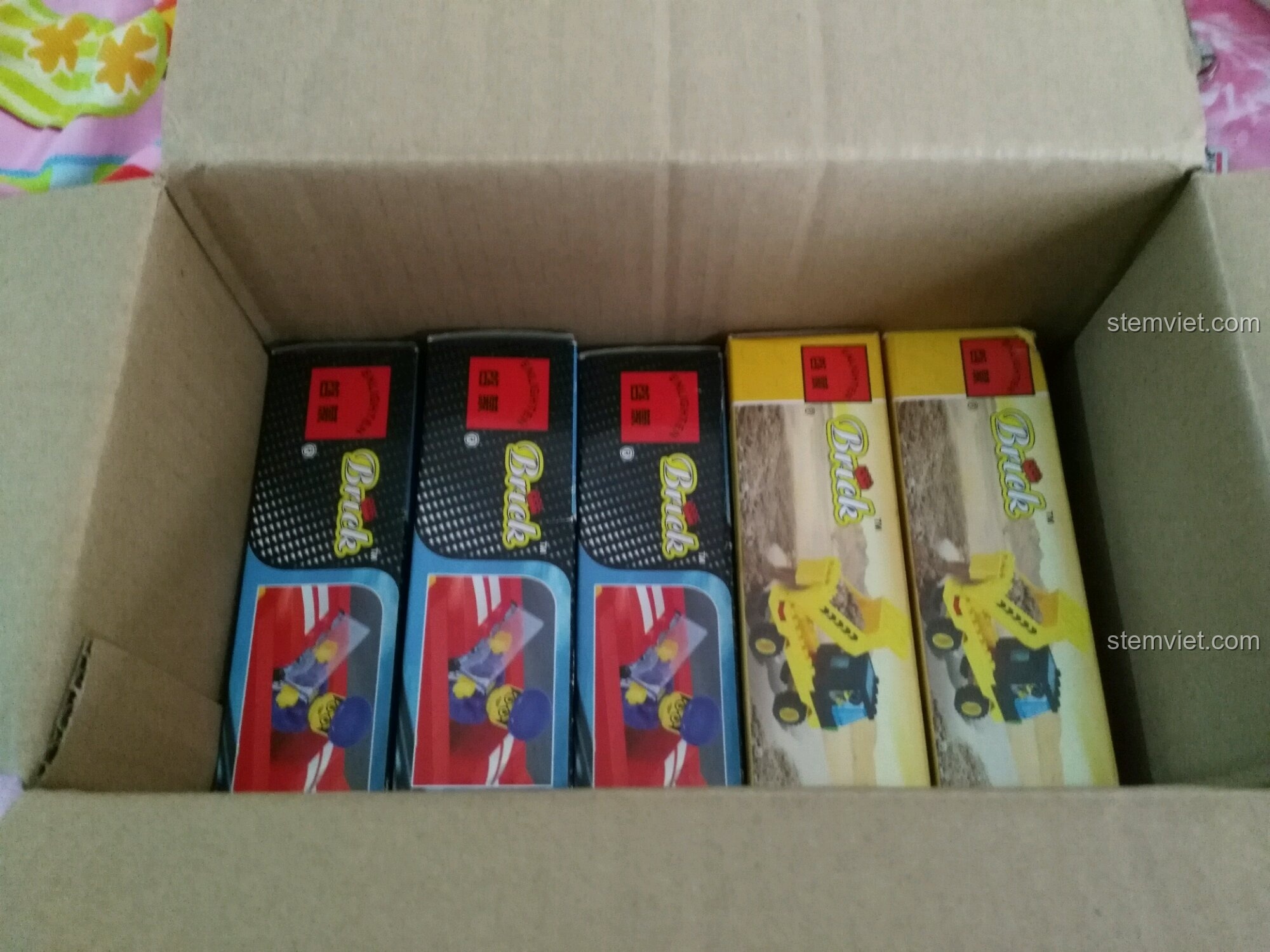 Thùng carton chứa các hộp đồ chơi lắp ráp Enlighten cổ điển, bao gồm xe đua 402 và xe ben 0381.