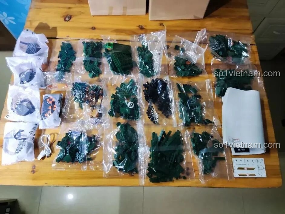 Toàn bộ chi tiết của bộ Sluban M38-B0850 trải ra trên bàn, bao gồm 15 túi gạch, bộ động cơ, sách hướng dẫn và sticker.