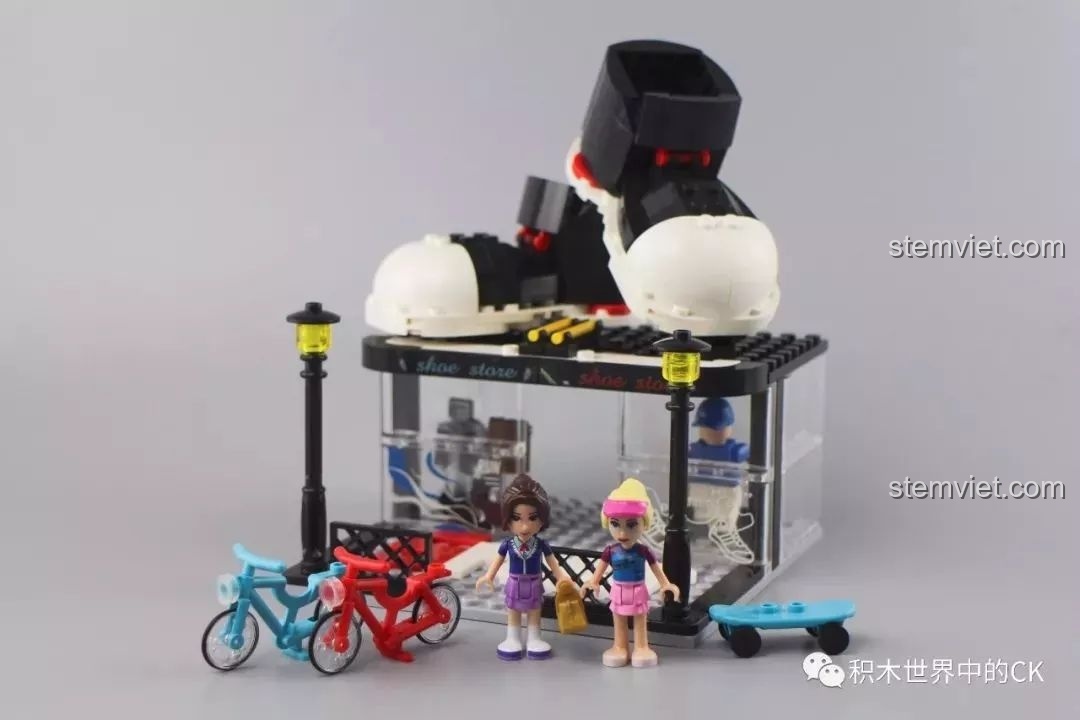 Toàn bộ khung cảnh của bộ Winner 5071 với hai minifigure, xe đạp và ván trượt trước cửa hàng.