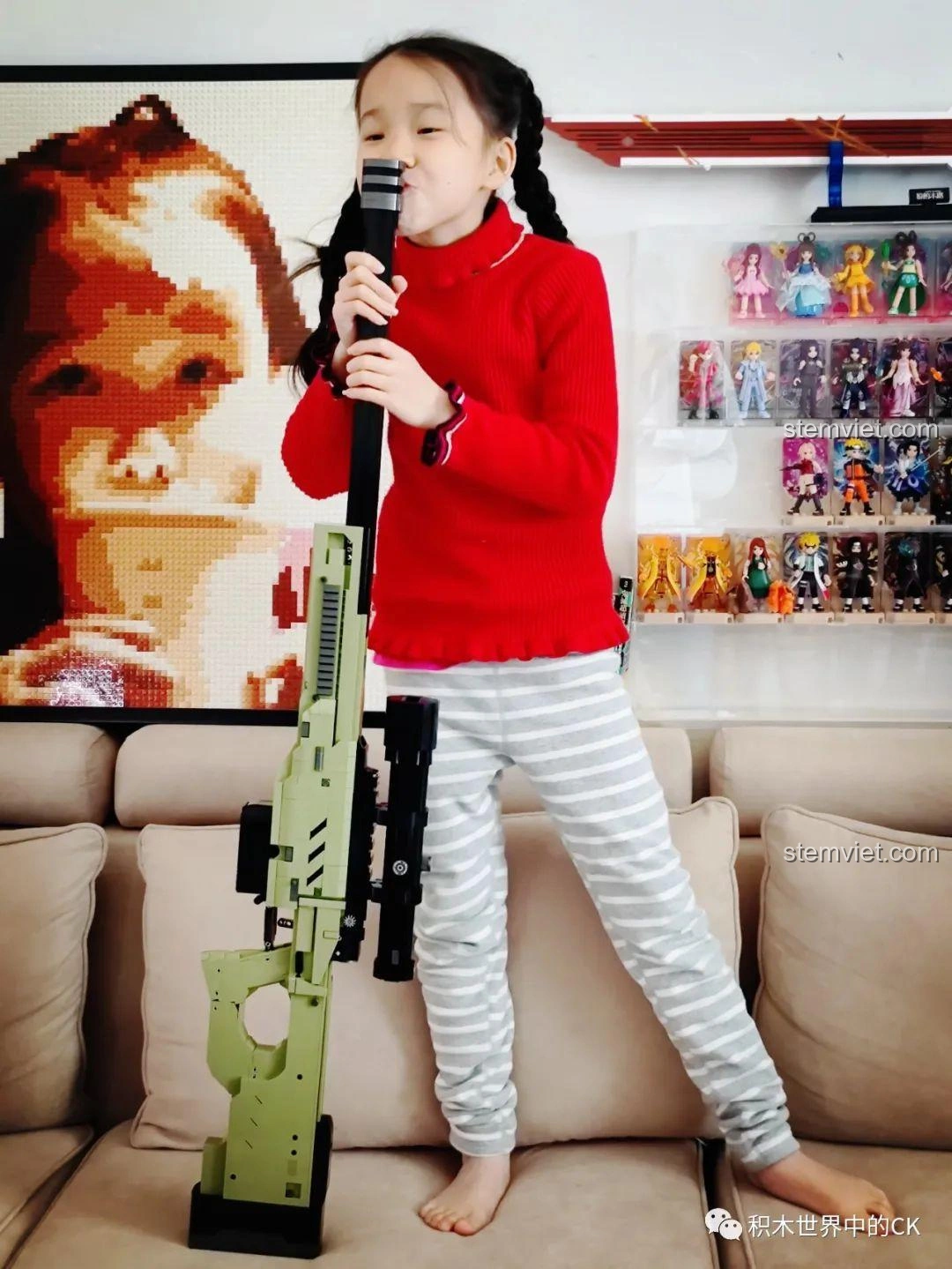 Bé gái đứng cạnh mô hình súng bắn tỉa AWP JIESTAR 58022, cho thấy chiều dài ấn tượng của sản phẩm.