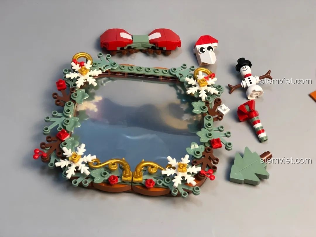 Các chi tiết trang trí như nơ, người tuyết, ông già Noel cho Gương Nhỏ Giáng Sinh JAKI, màu sắc hài hòa.