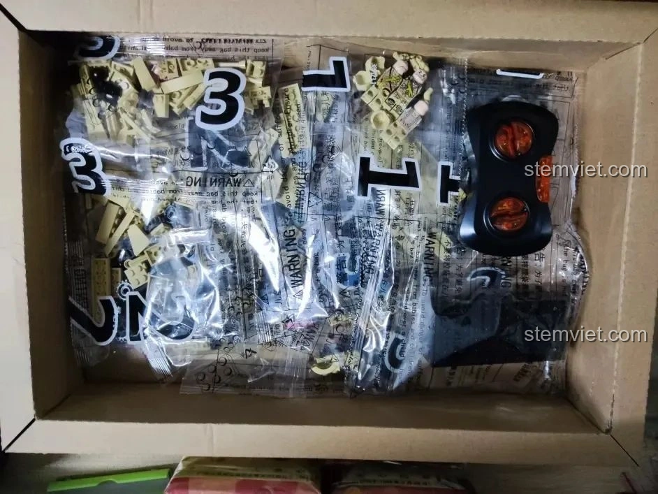 Các túi mảnh ghép và bộ điều khiển từ xa bên trong hộp bộ lắp ráp Xe Tăng Merkava HA389123.