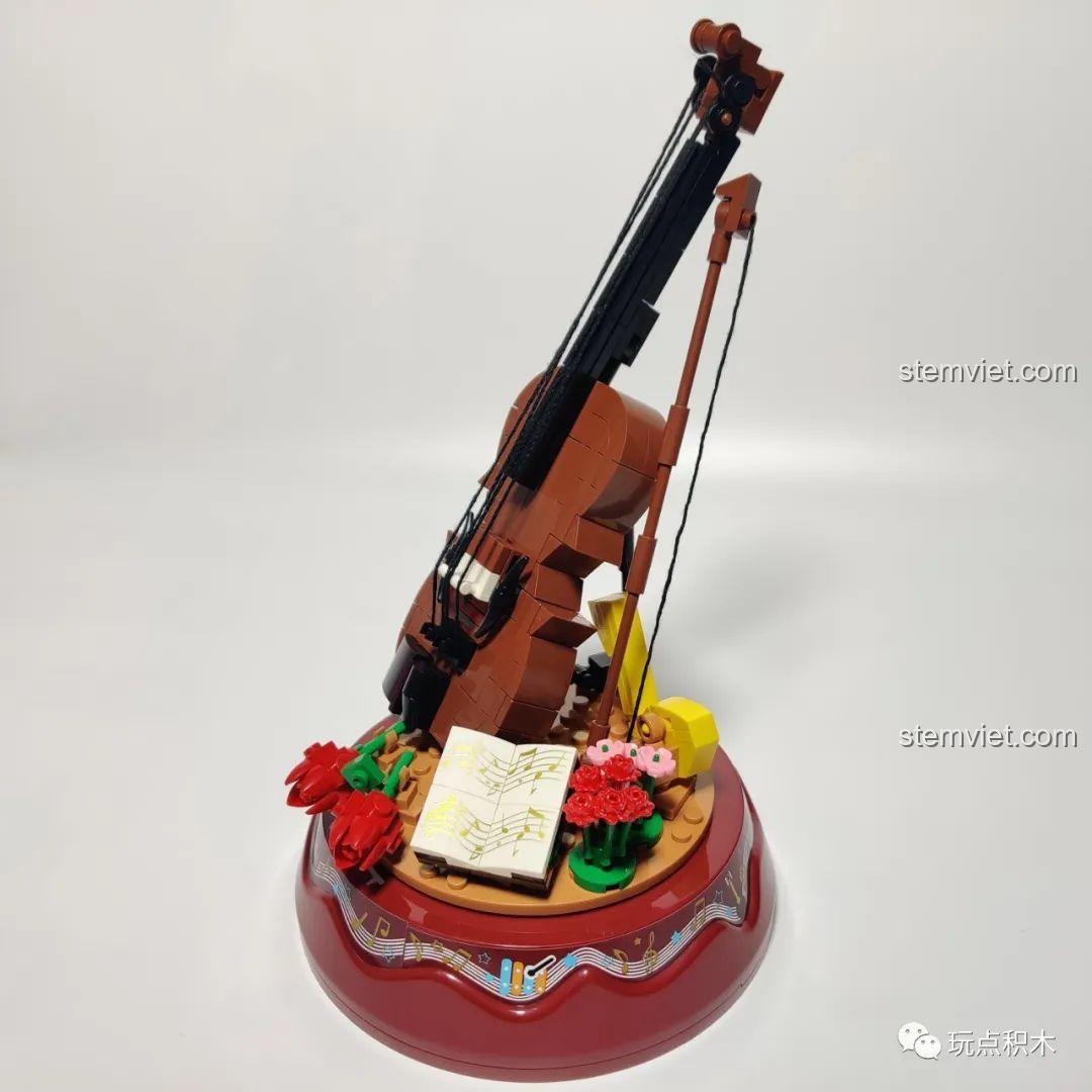 Mô hình đàn violin WOMA C0362 nhìn từ trên xuống, bên cạnh là bản nhạc và các chi tiết hoa lá.