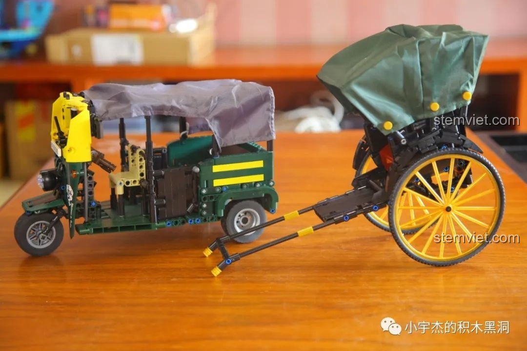 Mô hình xe kéo tay AchKo và xe lam được đặt cạnh nhau trên bàn gỗ, thể hiện vẻ đẹp riêng của mỗi mô hình.