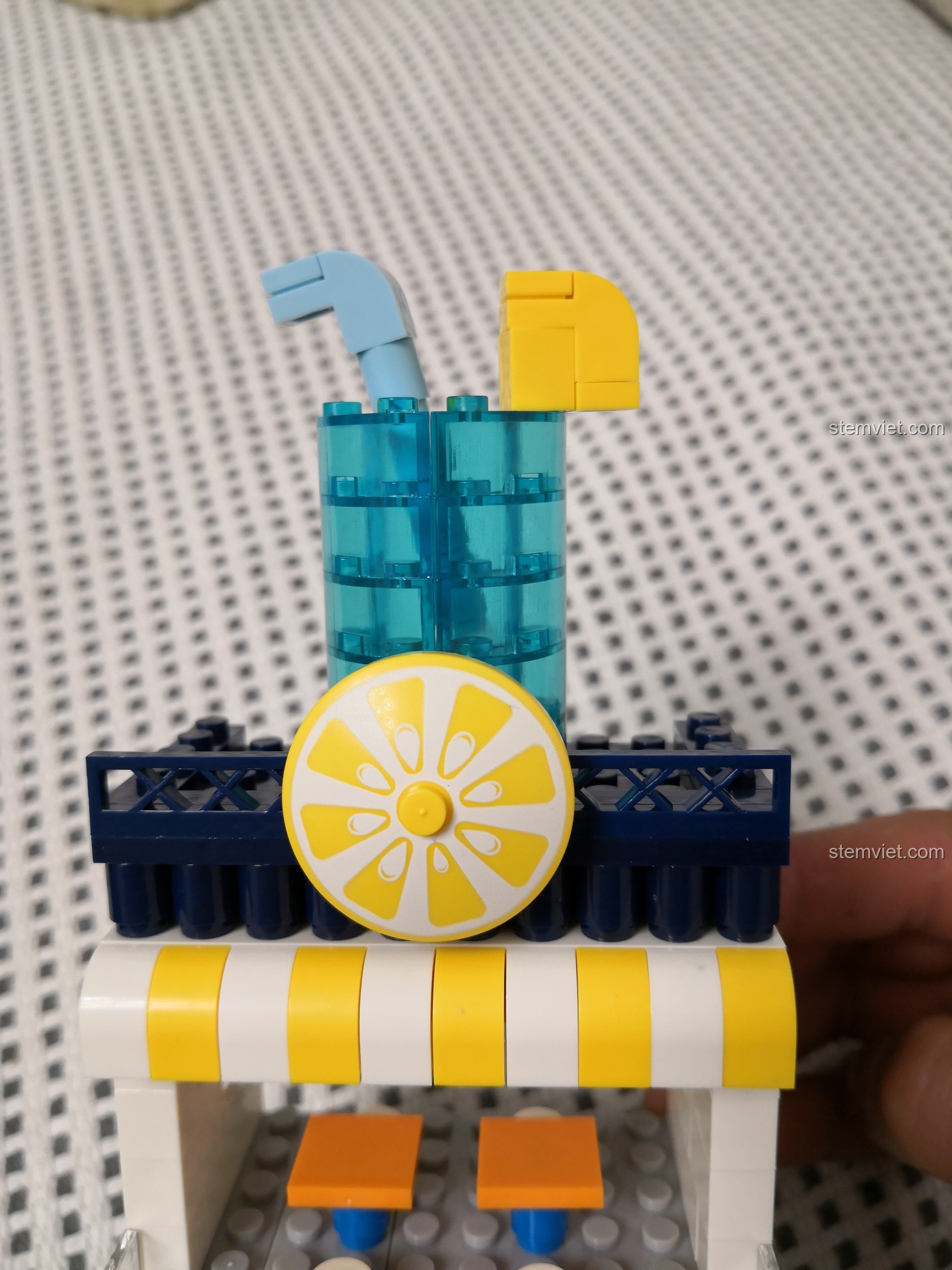 Cận cảnh ly nước ép màu xanh trong suốt và lát chanh vàng tươi trên nóc cửa hàng WANGE 2312.