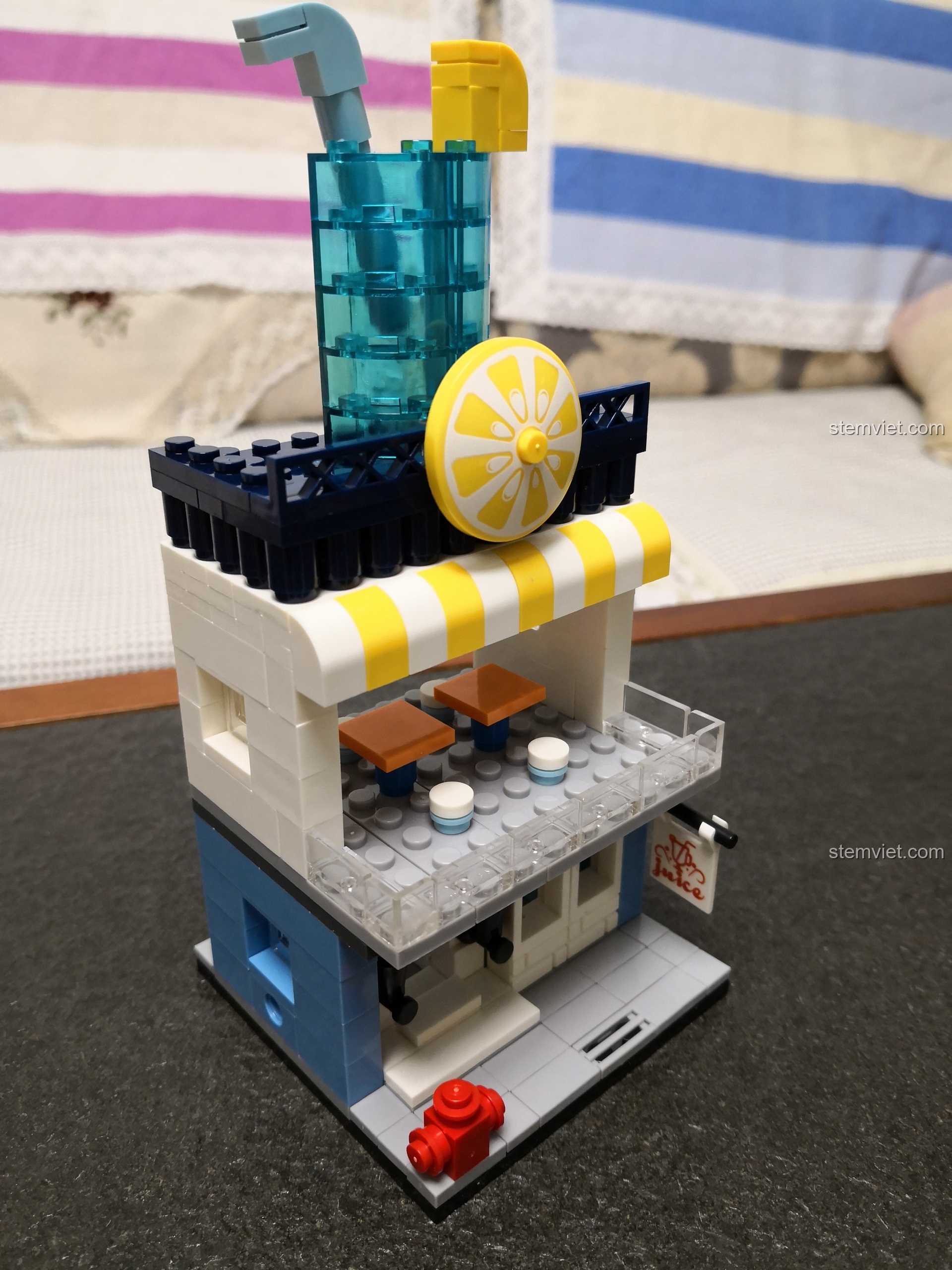 Toàn cảnh mô hình cửa hàng nước ép trái cây mini WANGE 2312, với ly nước lớn và lát chanh trên nóc.