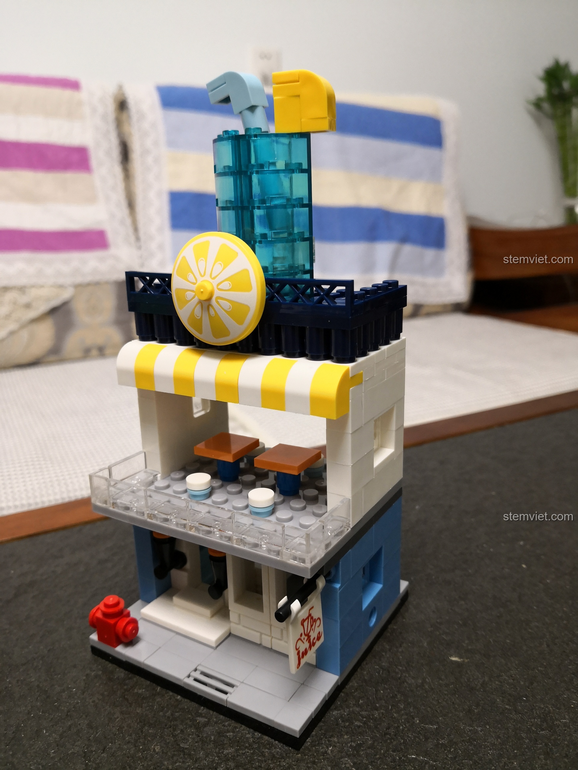 Cận cảnh vòi cứu hỏa màu đỏ nhỏ xinh ở góc dưới của mô hình cửa hàng nước ép WANGE 2312.