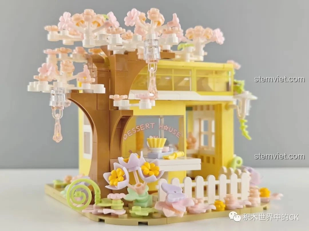 Mô hình hoàn chỉnh của bộ lắp ghép Wekki 516601 Tiệm Bánh Ngọt Hoa Anh Đào, nhìn từ góc nghiêng khác, nổi bật cây và hàng rào.
