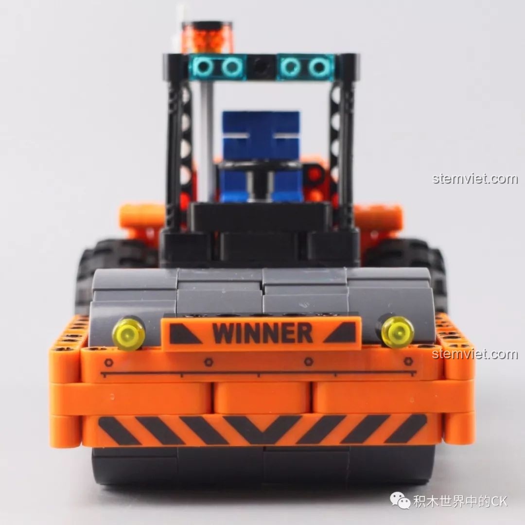 Mô hình xe lu Winner 7055 đã hoàn thành, nhìn từ phía trước, với con lăn lớn và đèn pha, thể hiện sự mạnh mẽ của xe công trình.