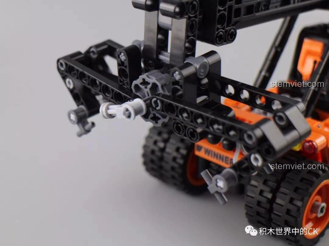 Bàn tay đang thao tác bộ phận gắp container trên mô hình Winner 7059 Xe Nâng Gắp Container, mô phỏng quá trình làm việc.