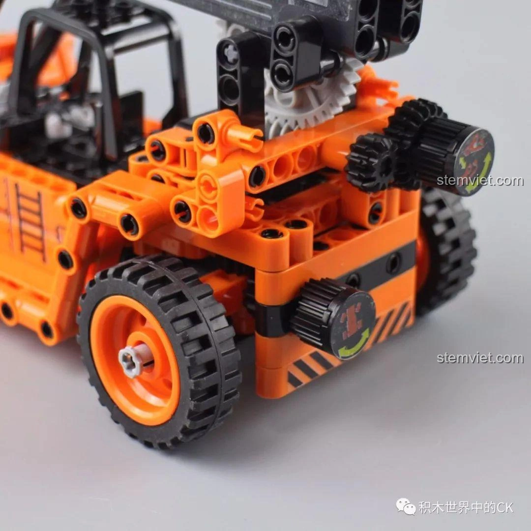 Bàn tay đang xoay núm điều khiển trên mô hình Winner 7059 Xe Nâng Gắp Container, kích hoạt cơ chế nâng hạ.