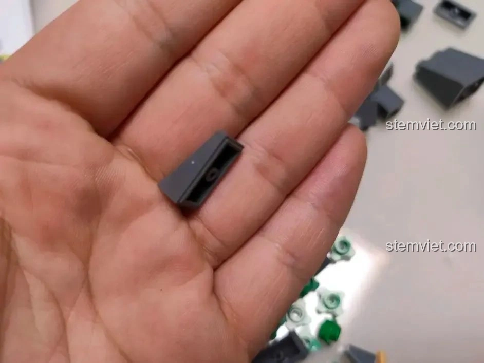 Cận cảnh một mảnh ghép dốc màu xám của bộ WOMA C0348 Đình Phượng Sơ trên lòng bàn tay, thể hiện độ hoàn thiện.