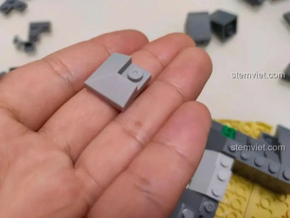 Cận cảnh một mảnh ghép phẳng màu xám của bộ WOMA C0348 Đình Phượng Sơ trên lòng bàn tay, cho thấy độ khít.