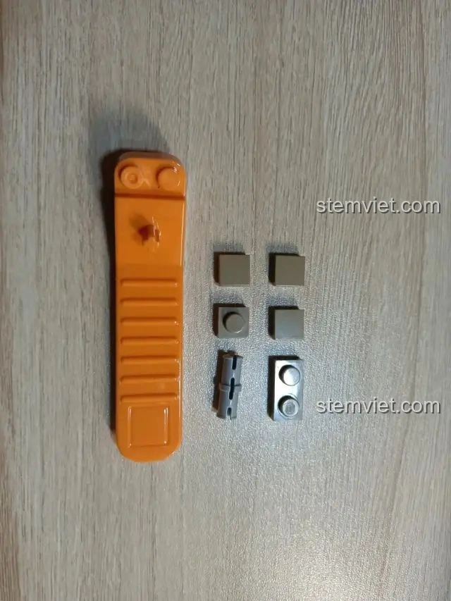 Dụng cụ tách mảnh ghép màu cam và một số mảnh ghép nhỏ của bộ Zhegao QL0176, hỗ trợ quá trình lắp ráp.