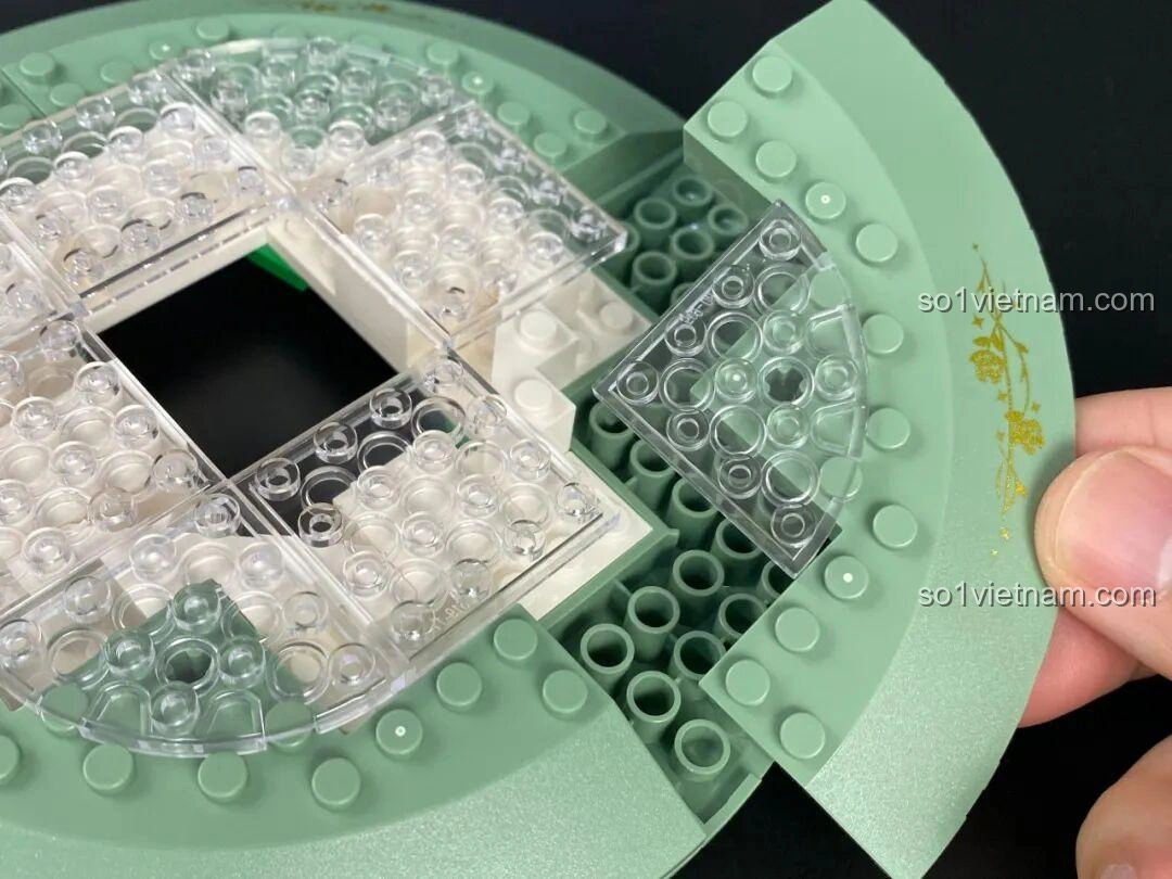 Lắp ráp mảnh ghép cong có họa tiết vàng cho phần đế của bộ Đồng Hồ Cát 86301.