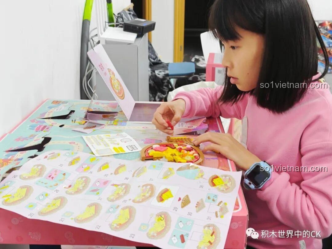 Một bé gái đang tập trung cao độ để lắp ráp một mô hình phức tạp từ bộ QMAN 35018, rèn luyện tính kiên trì.