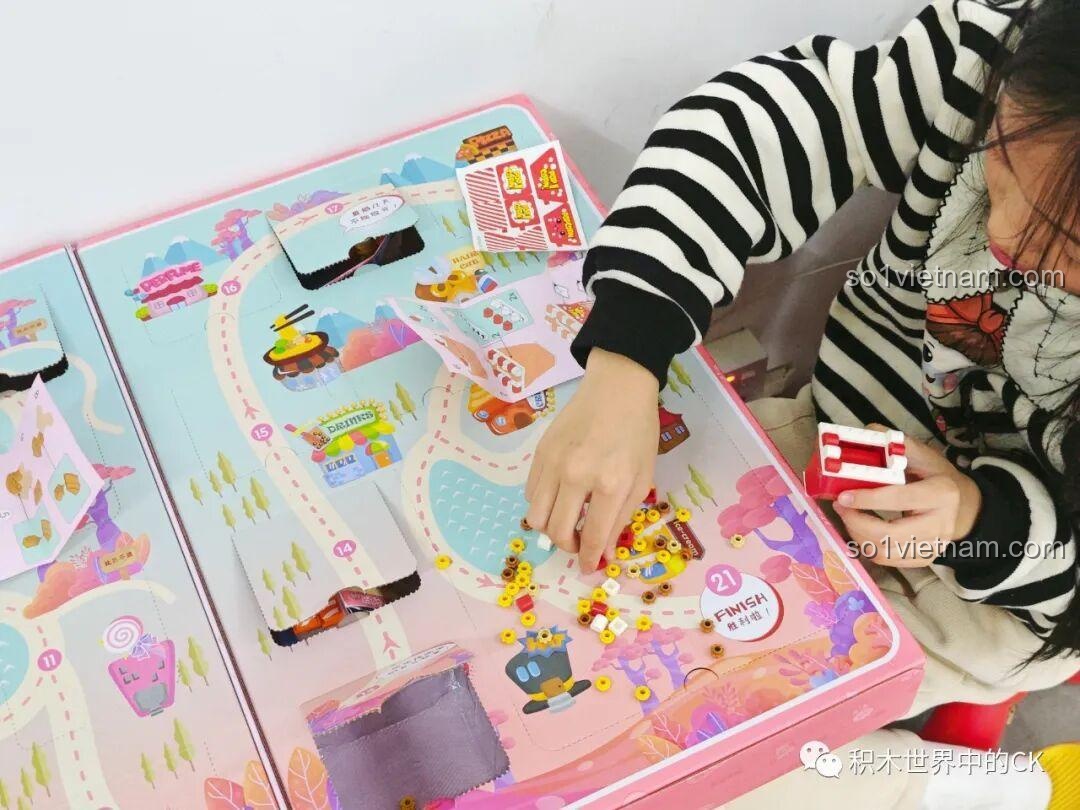 Một bé gái đang lắp ráp mô hình pizza từ các mảnh ghép nhiều màu của bộ QMAN 35018, thể hiện sự sáng tạo.