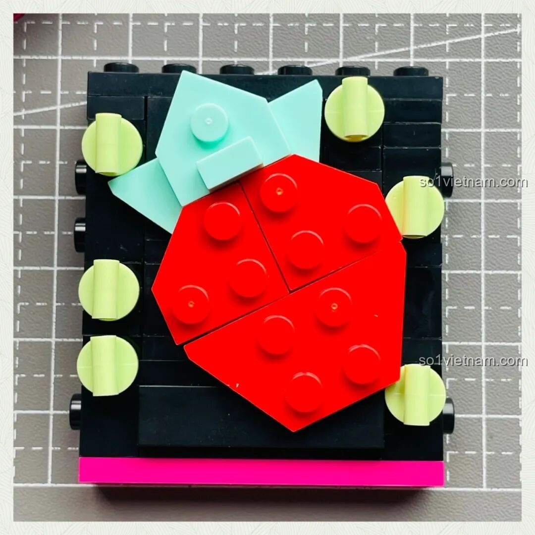 Bức tường hình quả dâu tây khổng lồ màu đỏ và xanh mint, biểu tượng của Strawberry Music Festival, trong bộ lắp ráp Ái Vũ Đài.