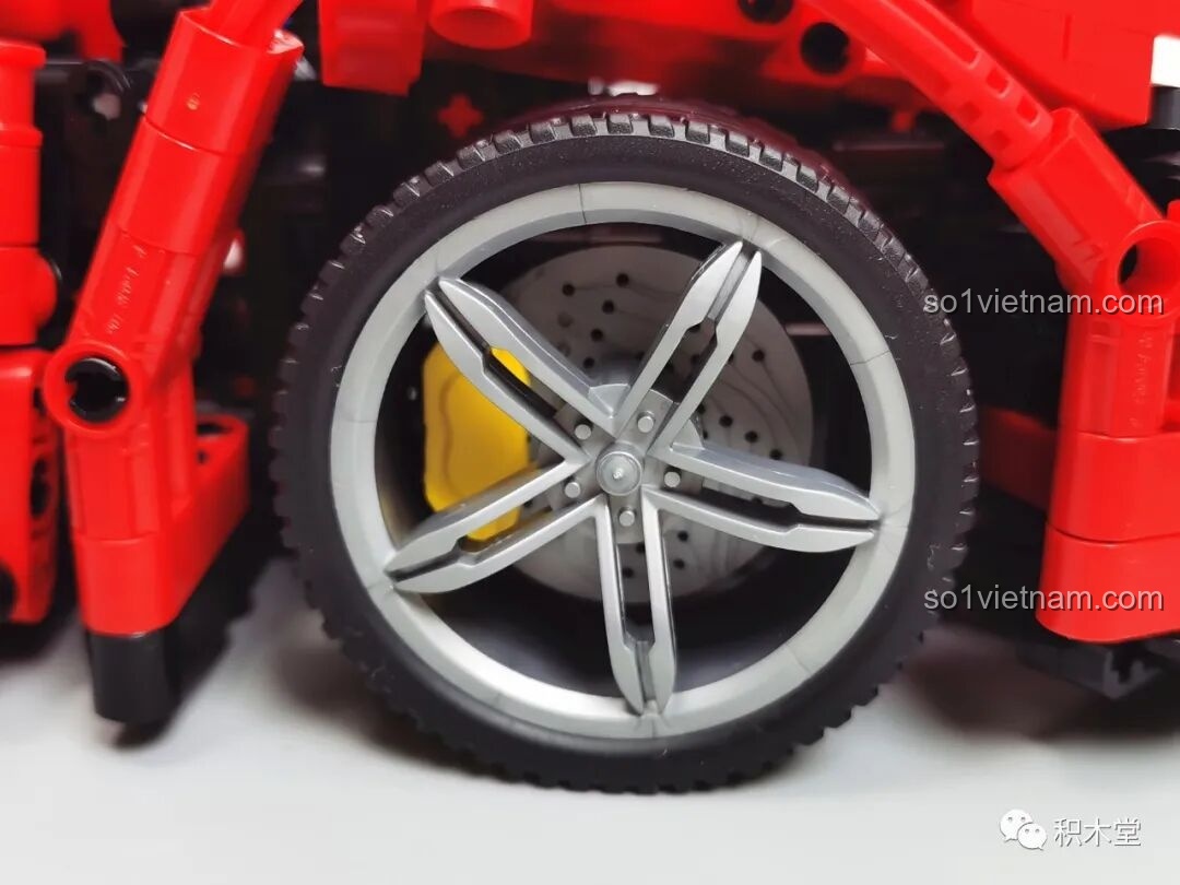 Cận cảnh bánh xe trước với mâm 5 chấu kép, đĩa phanh đục lỗ và kẹp phanh màu vàng nổi bật.