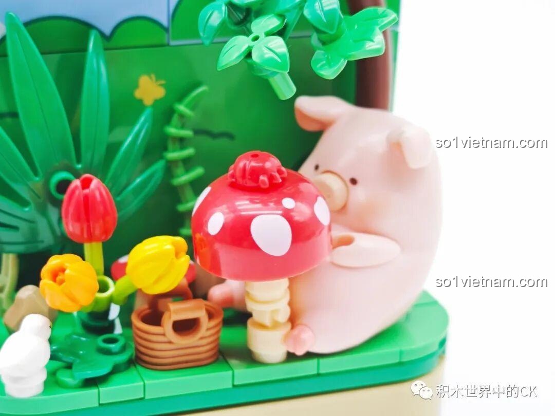 Cận cảnh Lợn LuLu ngồi bên cạnh cây nấm đỏ to và giỏ hoa quả trong bộ đồ chơi trang trí Lợn LuLu.