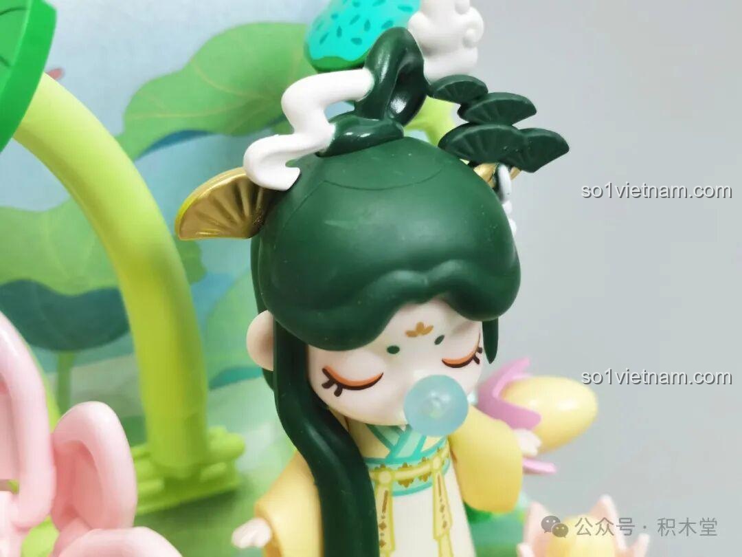 Ảnh chụp cận cảnh khuôn mặt của minifigure Nanci mùa Hạ, với đôi mắt nhắm và họa tiết trang trí trên trán.