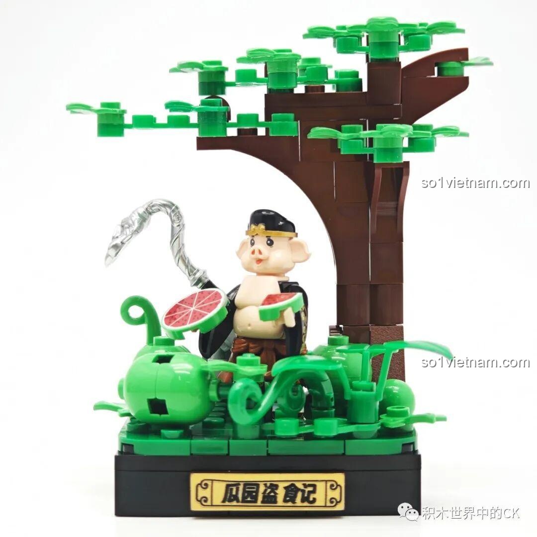 Góc nhìn chéo của mô hình Trư Bát Giới đang ngồi ăn dưa hấu dưới gốc cây.