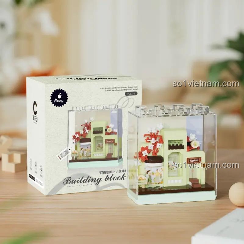 Hình ảnh đồ chơi mô hình Tiệm hoa mini 7370 bên cạnh vỏ hộp sản phẩm, thể hiện thiết kế xinh xắn và nhỏ gọn. Sản phẩm chất lượng cao cho bé gái.