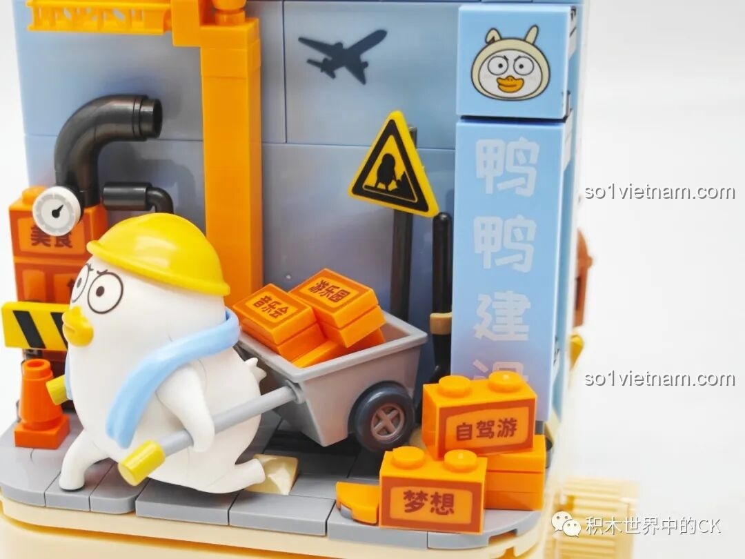 Cận cảnh các viên gạch xây dựng màu cam có in chữ và xe rùa trong bộ lắp ráp Vịt Liu công nhân.