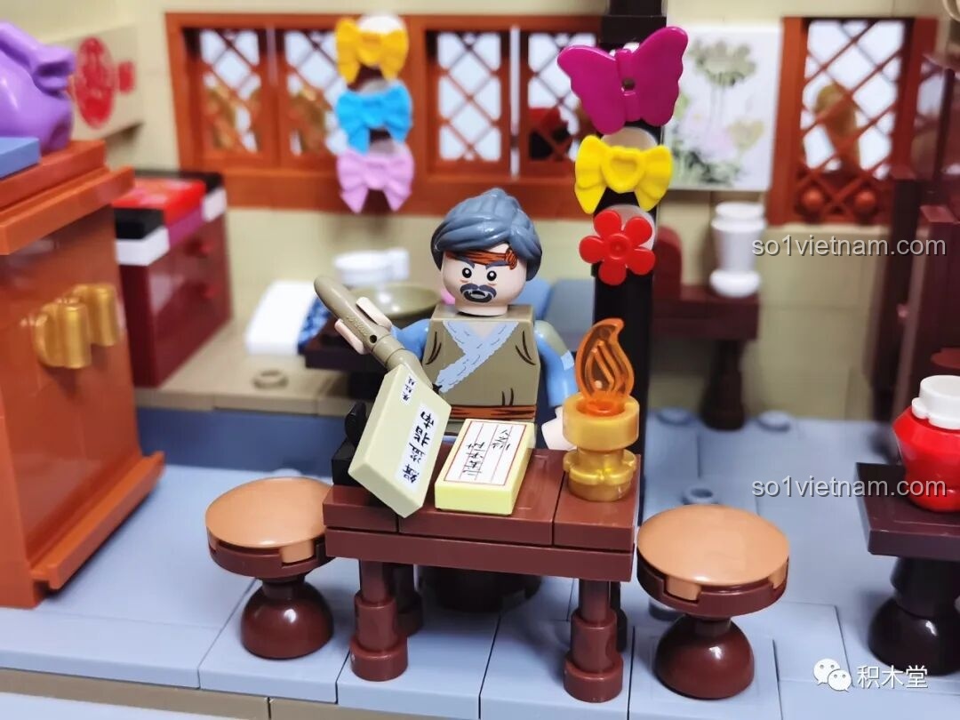 Cận cảnh một minifigure đang ngồi đọc sách bên bàn với đèn cầy.