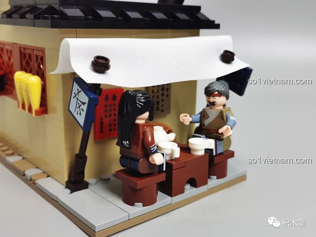 Cận cảnh hai minifigures đang ngồi uống trà tại quán nhỏ bên hông khách điếm.