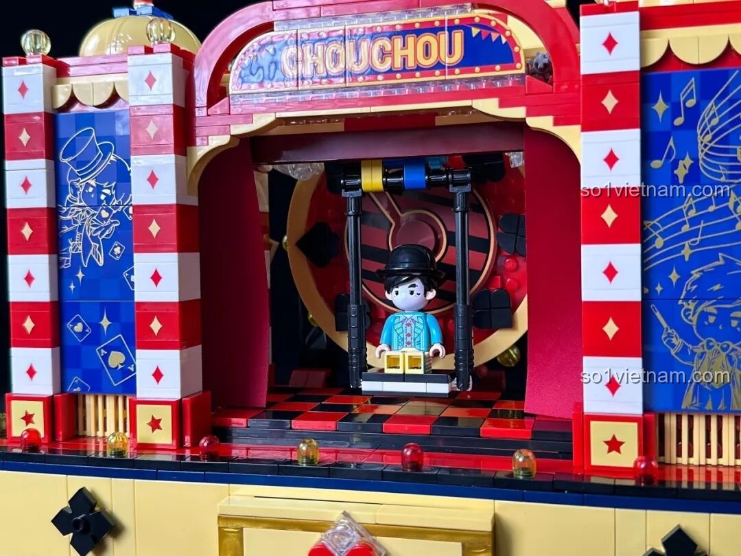 Một bàn tay đang xoay cần điều khiển để kích hoạt cơ chế xoay và thay đổi phông nền của sân khấu Keeppley K21302.